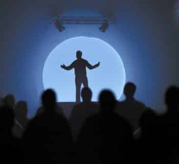 a silhouette of a man standing in front of a crowd