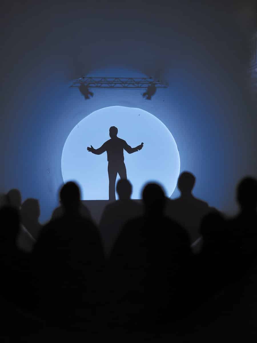 a silhouette of a man standing in front of a crowd